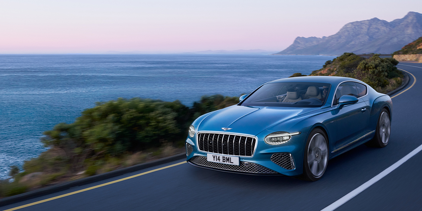 Bentley Oslo New Bentley Continental GT Azure coupe in Light Windsor blue paint with 22 inch Azure wheels and chrome grill, driving dynamically by the sea