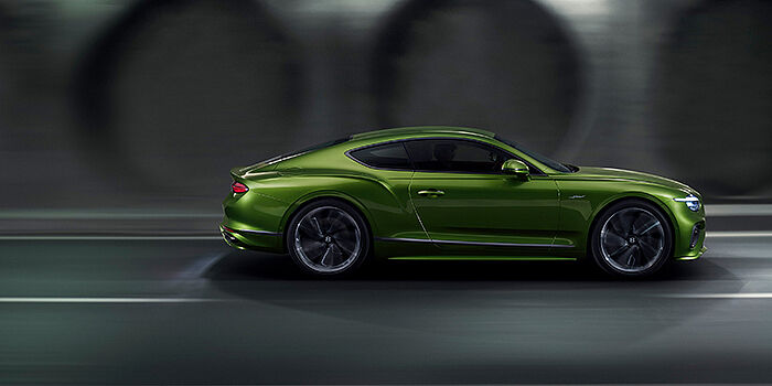  Bentley Oslo Bentley Continental GT coupe in Tourmaline Green paint driving in profile on a dark road